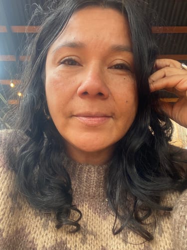 Cliente mostrando su cabello oscuro y ondulado tras usar el Polvo de Índigo.