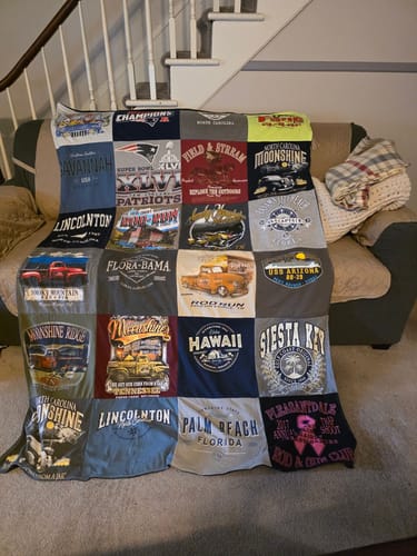 Customer's Project Repat T-Shirt Quilt, made from many different t-shirts, draped over a sofa.