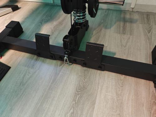 Rezensent zeigt die schwarze R7 SQUAT Backtube, die auf dem Boden eines Fitnessgeräts montiert ist.