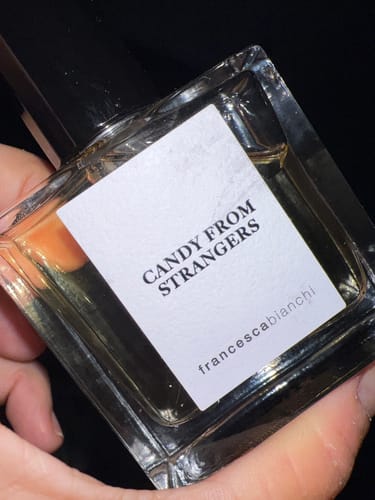 Primo piano del profumo Candy From Strangers tenuto in mano da un recensore.