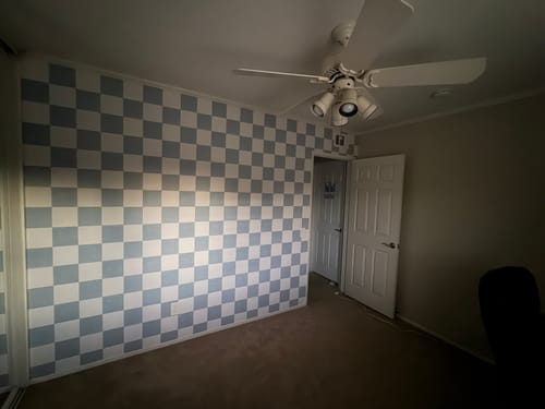 Customer's bedroom with the blue and white checkered Devin Wallpaper installed on an accent wall.