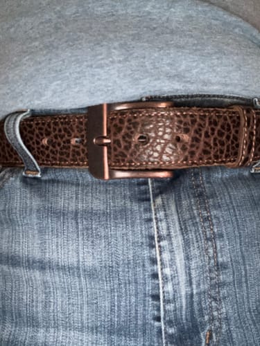 Close-up of a reviewer wearing the textured brown Yellowstone belt with blue jeans.