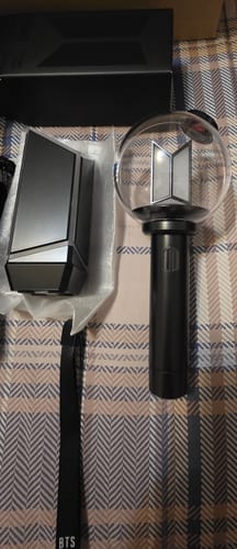 Customer's BTS Official Light Stick Ver.4 and its cradle unboxed on a plaid surface.