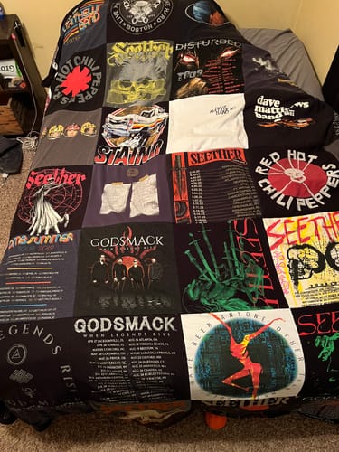 Customer's large Project Repat T-Shirt Quilt made from various rock band t-shirts, spread across a bed.