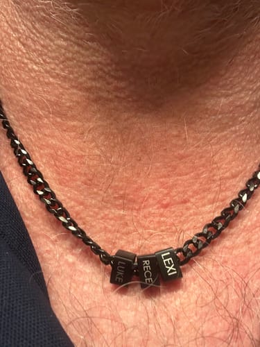 Customer wearing their personalized Legacy necklace with three black beads engraved with names.