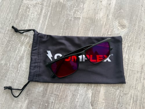 Customer's black Neurospecs glasses with red lenses resting on the black carrying pouch.