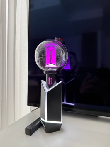 Reviewer's BTS Official Light Stick Ver.4 illuminated in purple and set in its display cradle.