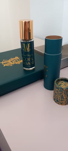 Customer's Copacabana fragrance bottle with its teal packaging and gold accents on a desk.