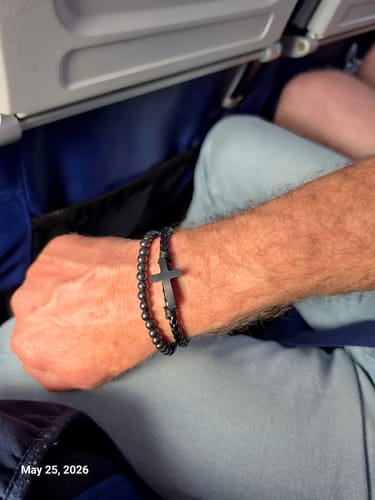 Customer's wrist wearing the FIDES Cross bracelet, showing the black beaded band and central cross.