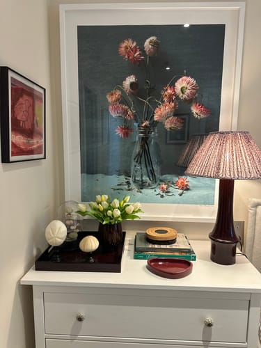 Customer's white short stem tulips displayed in a small vase on a white dresser.
