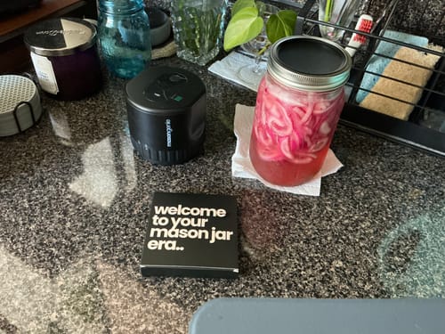 Customer's black Mason Genie Vacuum Sealer on a kitchen counter next to a large mason jar of pickled onions.