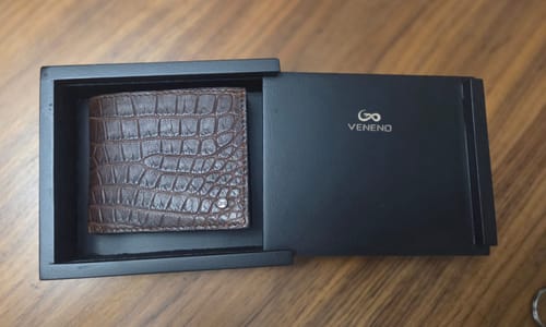 Cliente muestra la Cartera "The Grid" de cocodrilo marrón dentro de su caja negra.
