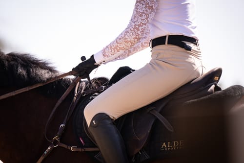Partial view of a customer riding a horse, showing the elegant lace sleeve of the Jaclyn Lace Long Sleeve Show Shirt.
