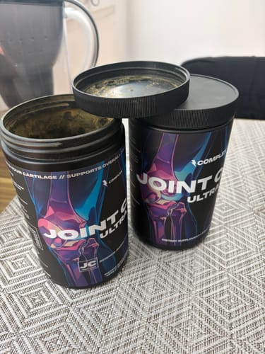 Reviewer shows their finished tub of Joint Care Ultra on a table next to a new, unopened one.
