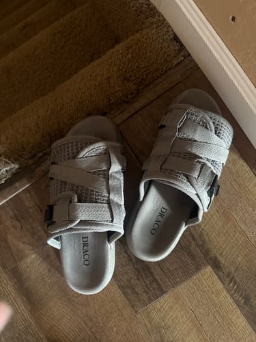 Customer's top-down view of the light gray Reflective Dracoslides on a wooden floor near carpeted stairs.