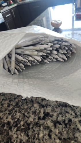 Customer shows a bubble mailer full of pens received instead of the Legacy Necklace.