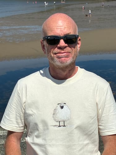 A reviewer wearing the off-white Sheep t-shirt outdoors near the water.
