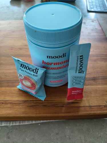 Reviewer's Strawberry Watermelon electrolyte packet shown with other Moodi products on a wooden board.