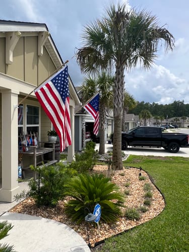 Customer's Bennington Flag flying on a house exterior, seen behind a modern American flag.