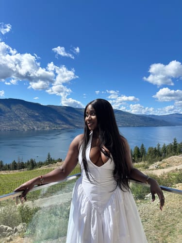 Customer wearing the white Atalia Sundress with a halter top, posing outdoors by a scenic lake.
