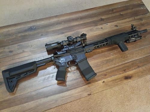 Customer's black Raid Tape wrapped around the handguard and foregrip of a rifle on a wooden table.
