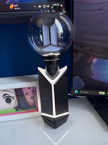 Customer's BTS Official Light Stick Ver. 4 in its cradle, both lit up on a desk.
