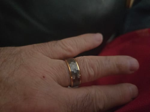 Customer's hand wearing the Sovereign ring, showing its textured dark center and gold-tone edges.