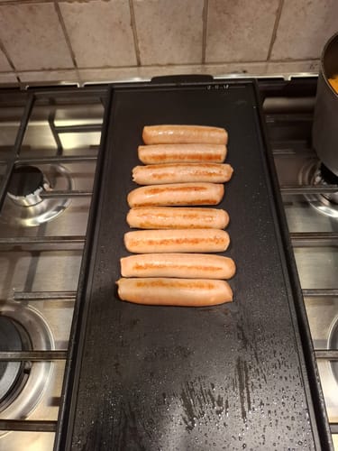 Reviewer's Chicken Breakfast Sausages cooking on a long black griddle on the stovetop.