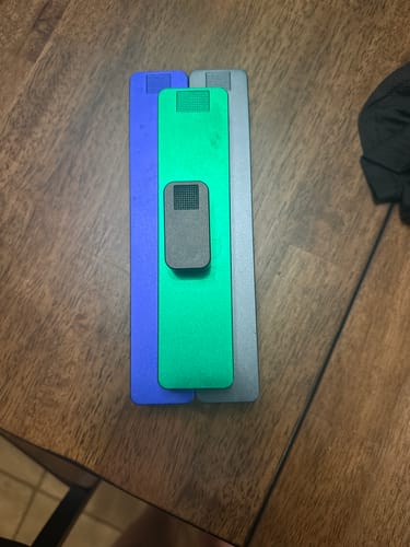 Customer's colorful metal Weekly AM-PM Vitamin Cases in blue, green, and gray on a wooden surface.