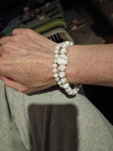 Reviewer's wrist wearing two stacked white Howlite bead bracelets, one with a heart bead.