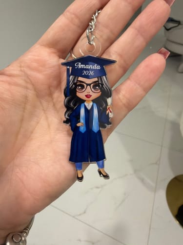 Customer's personalized acrylic keychain showing a female graduate with dark hair in a blue cap and gown.
