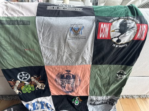 Customer's Project Repat T-Shirt Quilt made from colorful work shirts, draped over the back of a sofa.
