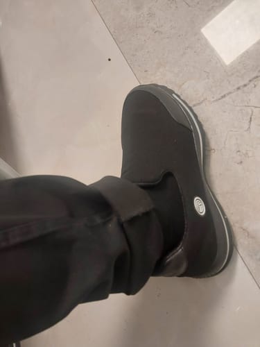 Close-up of a reviewer wearing one black Bacca Bucci walking shoe with rolled-up trousers.