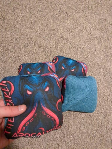 Reviewer holding The Kraken Pro Series bag, showing the detailed graphic front and the plain teal carpet back.