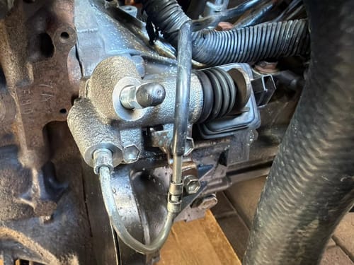 Customer's new Clutch Slave Cylinder installed in a car engine, showing the metallic part with hoses connected.