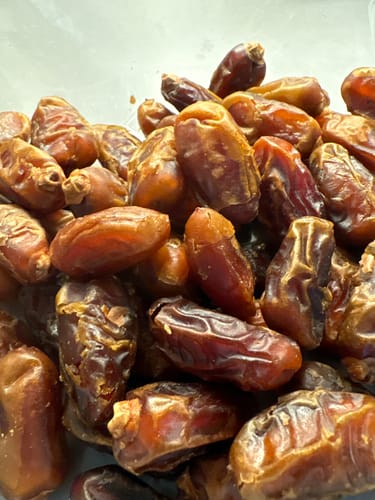 Customer's close-up of a pile of fresh, golden Organic Halawi Dates.