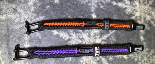 Customer's photo of two black paracord bracelets, one with orange and one with purple stitching.