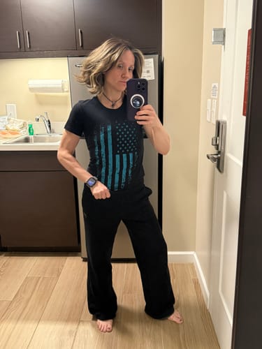Reviewer wearing the black Distressed Flag women's t-shirt, showing its slim fit in a full-length mirror picture.