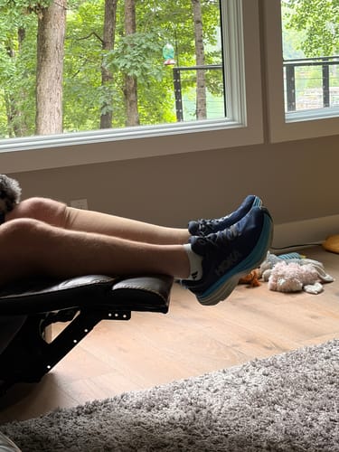 Customer relaxing with their feet up, wearing white Eucalyptus Lyocell Compression Socks and sneakers.