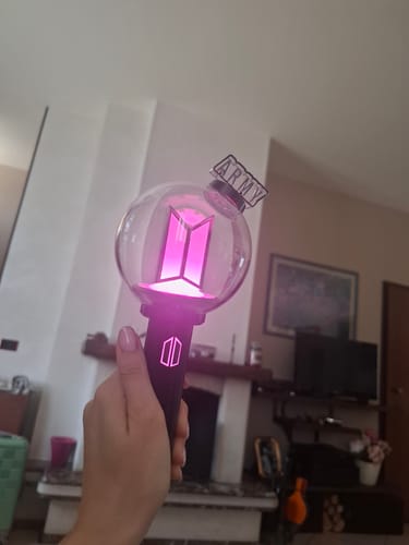 Customer holding the BTS Official Light Stick Ver.4, which is glowing bright pink with the 'ARMY' part attached.