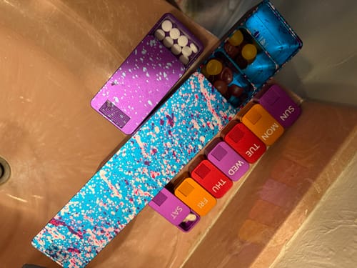 Customer's collection of pill cases, including the colorful Weekly Case, holding various pills and gummies.