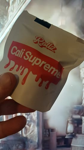 Reviewer holding the white and red package for CALI SUPREME THCA Flower.