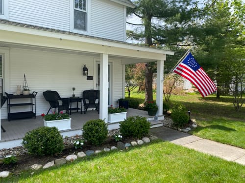 Customer's beautiful Betsy Ross flag flying from the porch of a white house.