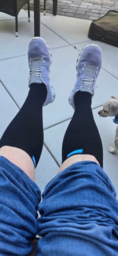 A customer's view of their legs propped up while wearing black Eucalyptus Lyocell Compression Socks outdoors.