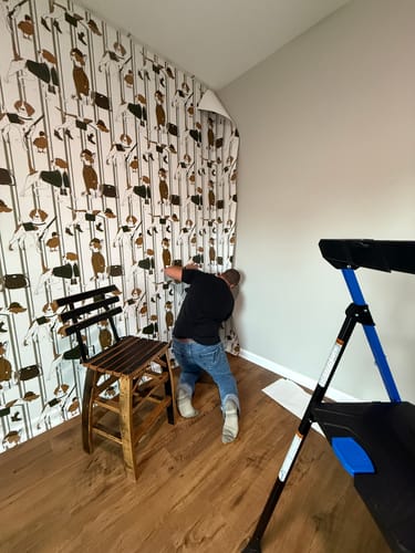 Reviewer applying the patterned Edmund Wallpaper in the corner of a room.