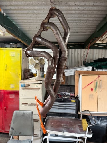 Customer's rusty exhaust system hanging in a garage before being painted.