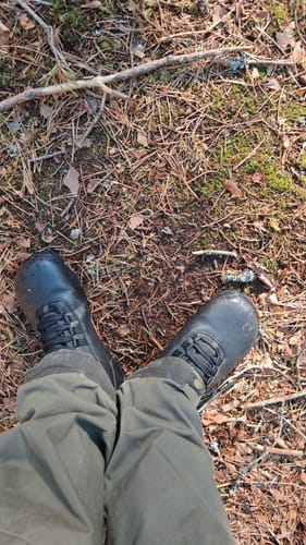 Arvostelijan mustat Vaistoa Uoma 2 -kengät jalassa metsämaastossa.