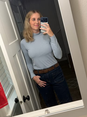 Reviewer wearing the light-blue Farrah Star Turtleneck Training Top tucked into dark jeans.
