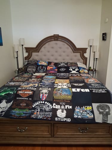 Customer's large Project Repat T-Shirt Quilt, a patchwork of various graphic tees, spread across a bed.