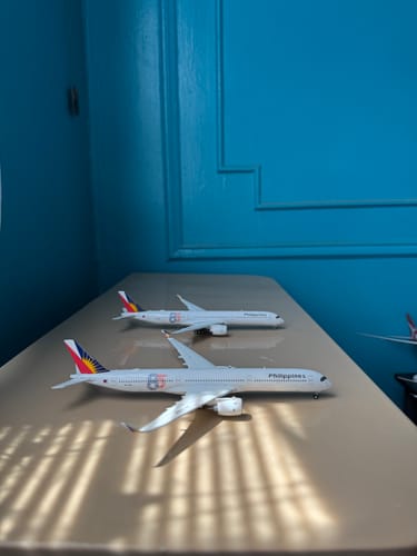 Customer's two GEMINI PHILIPPINE A350-1000 model airplanes displayed on a desk against a blue wall.